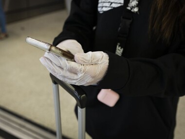 A person holding a cell phone in gloved hands