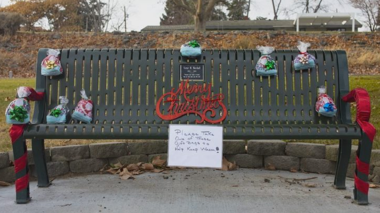 Bench decorated with Christmas sign and bags of gifts