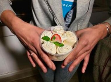 person’s hands holding a tub of rolled ice cream