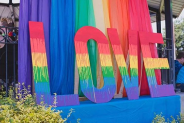 Rainbow colored, large letters spelling love sitting in front of an outdoor stage