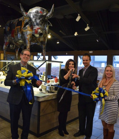 People with giant scissors cutting ribbon