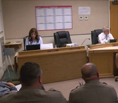 Three people sitting at desks in a meeing room