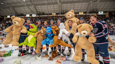 Hockey players on ice with giant teddy bears