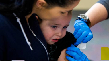 woman holding a child who's getting a vaccine