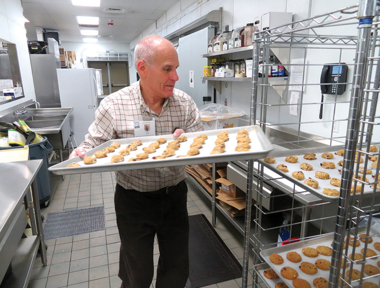 man stacking tray of cookies to be baked