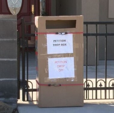 Cardboard box with paper that says petition drop box and petition drop off on it