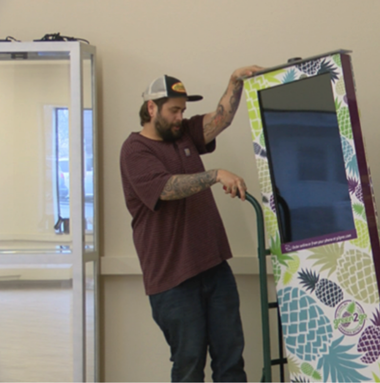 Green2Go employee moving marijuana dispenser on a hand truck