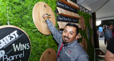 Noel Perez signs his name onto a wine barrell lid