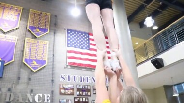 hands holding reaching up and holding a cheerleader in the air by their feet