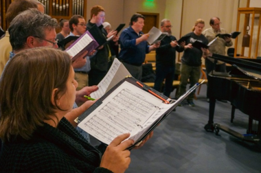 People standing in a circle and singing out of choir books