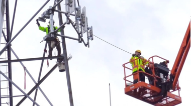 two adults in safety gear repairing power lines