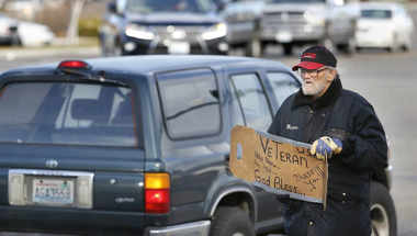homeless veteran holding sign on street