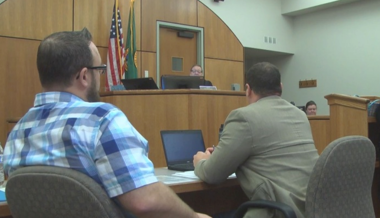 two men sitting in chairs facing a judge in a court room