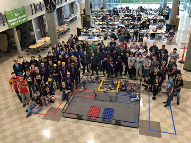 teams of students gathered around robots