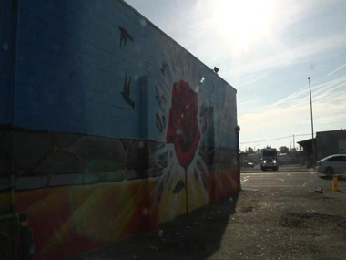 Mural of a rose with doves flying away from it on the back of Vinny's Bakery in Pasco