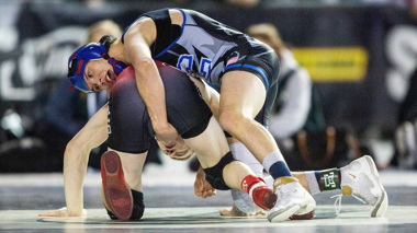 two wrestlers wrestling on mats