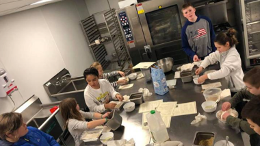 kids rolling dough by hand in a commercial kitchen