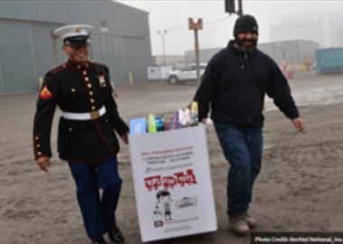 Air Force officers carrying toys for tots sign