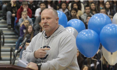 Football coach standing in front of blue balloons