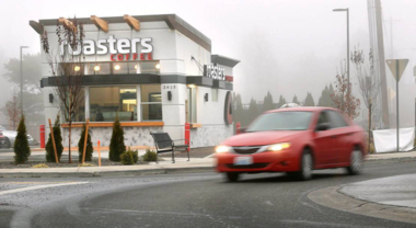 Car driving around roundabout with roasters shop in the background
