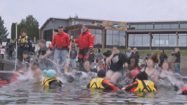 people splashing around in water with life jackets while spectators look