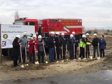 Firefighters in a line digging into dirt with shovels