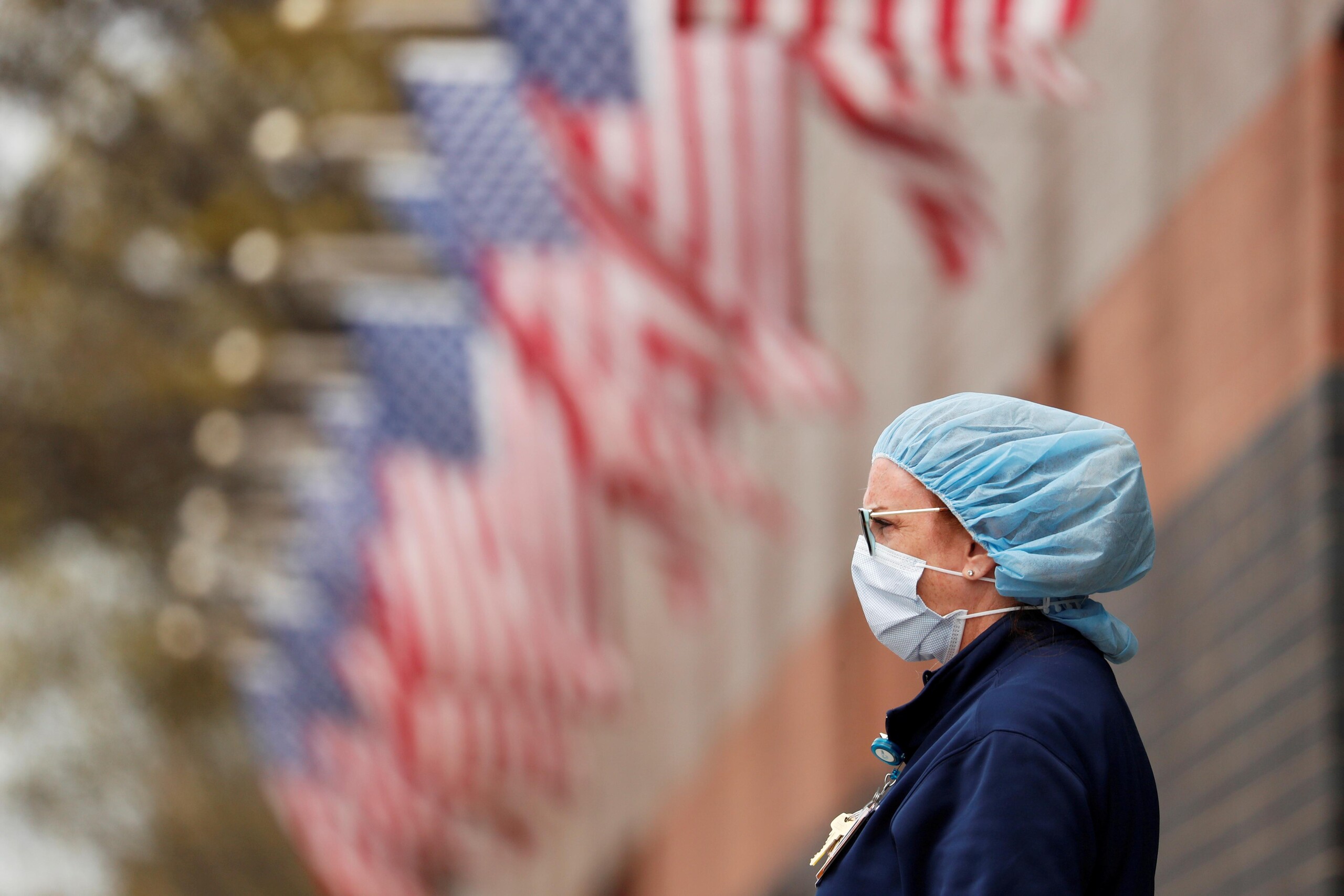 A nurse wearing personal protective equipment watches an ambulance driving away outside of Elmhurst Hospital during the ongoing outbreak of the coronavirus disease (COVID-19) in the Queens borough of New York, U.S., April 20, 2020.