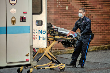 A patient beeing wheeled out of an ambulance, on a streatcher and into a hospital