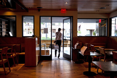 A person leaving a restaurant with bags of takeout