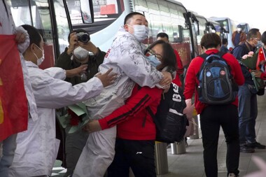 A medical worker from China's Jilin Province, in red, embraces a colleague from Wuhan as she prepares to return home at Wuhan Tianhe International Airport in Wuhan in central China's Hubei Province, April 8, 2020